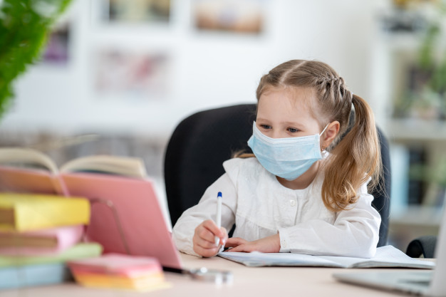 bambina-carina-in-maschera-fare-i-compiti-e-learning_127093-1975