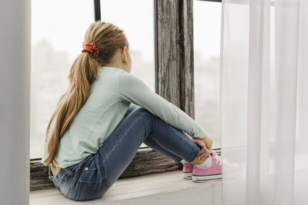 side-view-little-girl-sitting-window-sill_23-2148813180