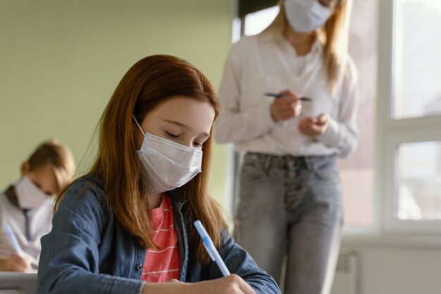 children-with-medical-masks-learning-school-with-female-teacher_23-2148848255