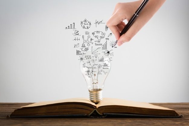 person-drawing-symbols-coming-out-light-bulb-top-book_1232-907