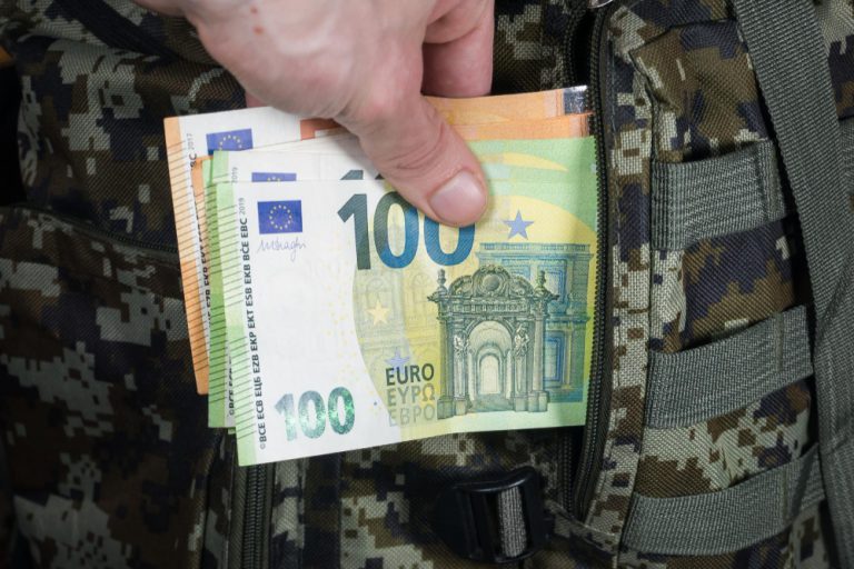 man-is-putting-in-a-military-backpack-eurosxadark-green-camouflage-khaki-bag-with-money-migrants-and-refugees-concept