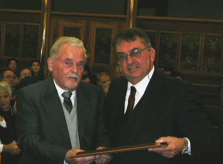 2002 – GioBatta Rossi riceve una targa dal presid. CMA Rizieri Ongaro per gli 80 anni e per il contributo dato in campo linguistico ed etnografico