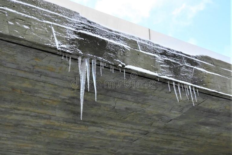 falci-del-ghiaccio-che-appendono-fuori-dal-lato-di-un-tetto-inverno-della-neve-146094984