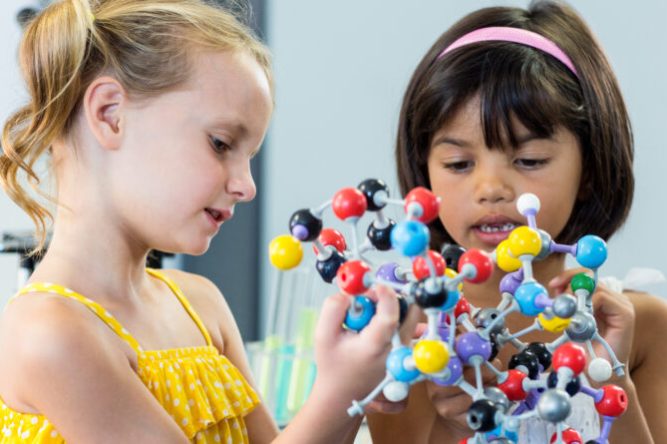 Cute girls holding DNA model in classroom
