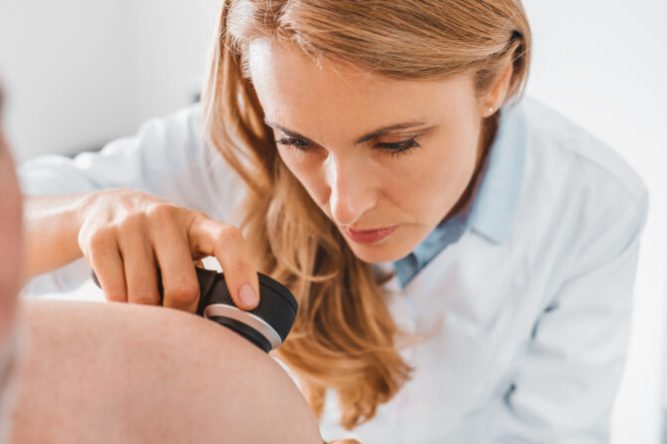 Doctor dermatologist examines skin of patient. Dermatoscopy, prevention of melanoma, skin cancer.