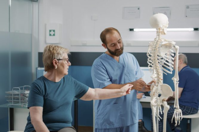 Osteopath explaining orthopedic diagnosis on human skeleton