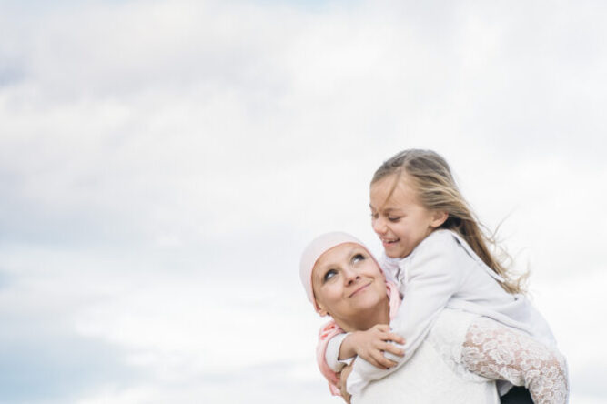 A woman with cancer is  next to her daughter. A girl is hugging